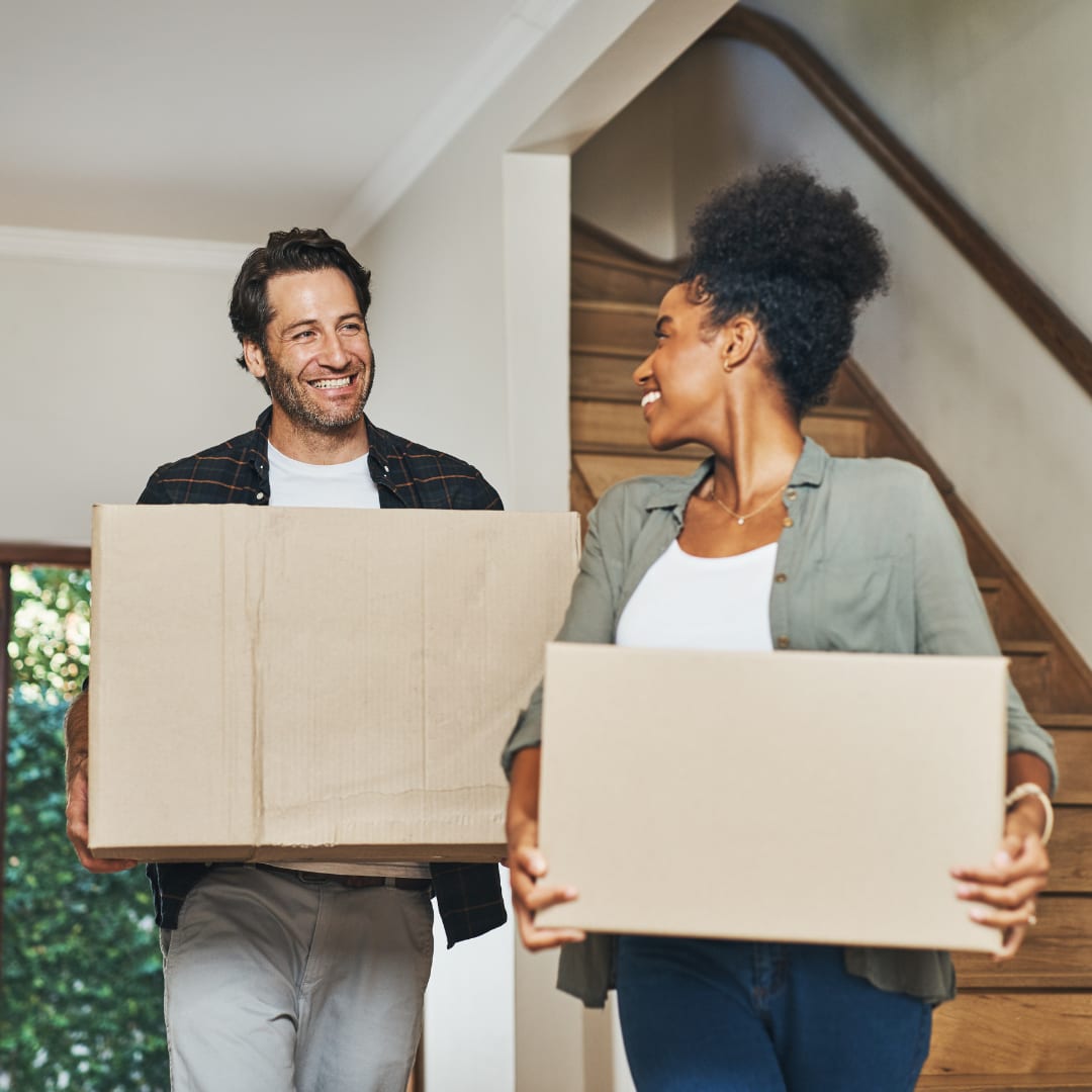 A happy couple carrying moving boxes into their new home
